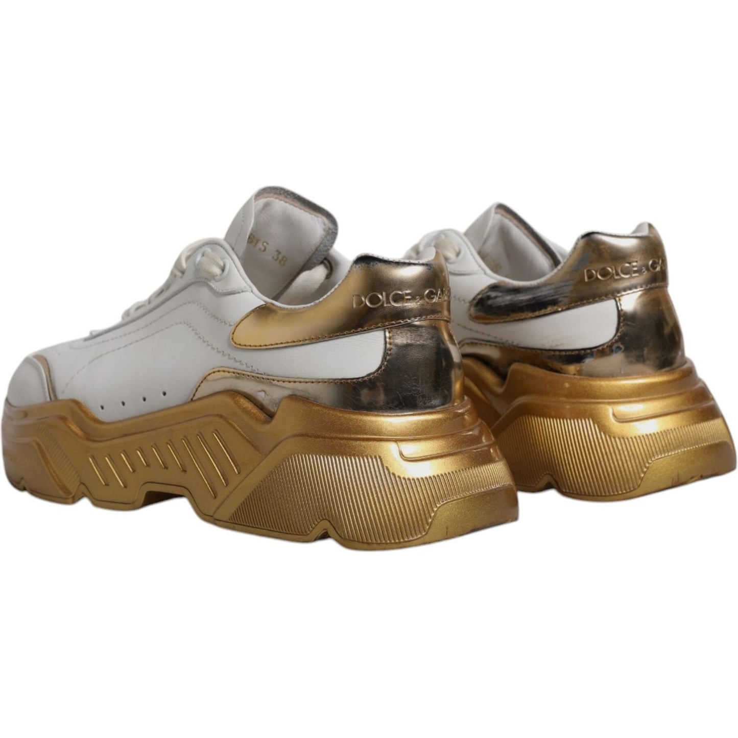 Dolce & Gabbana Daymaster sneakers in white leather with gold accents, showing logo and distinctive rubber sole, lace-up closure.