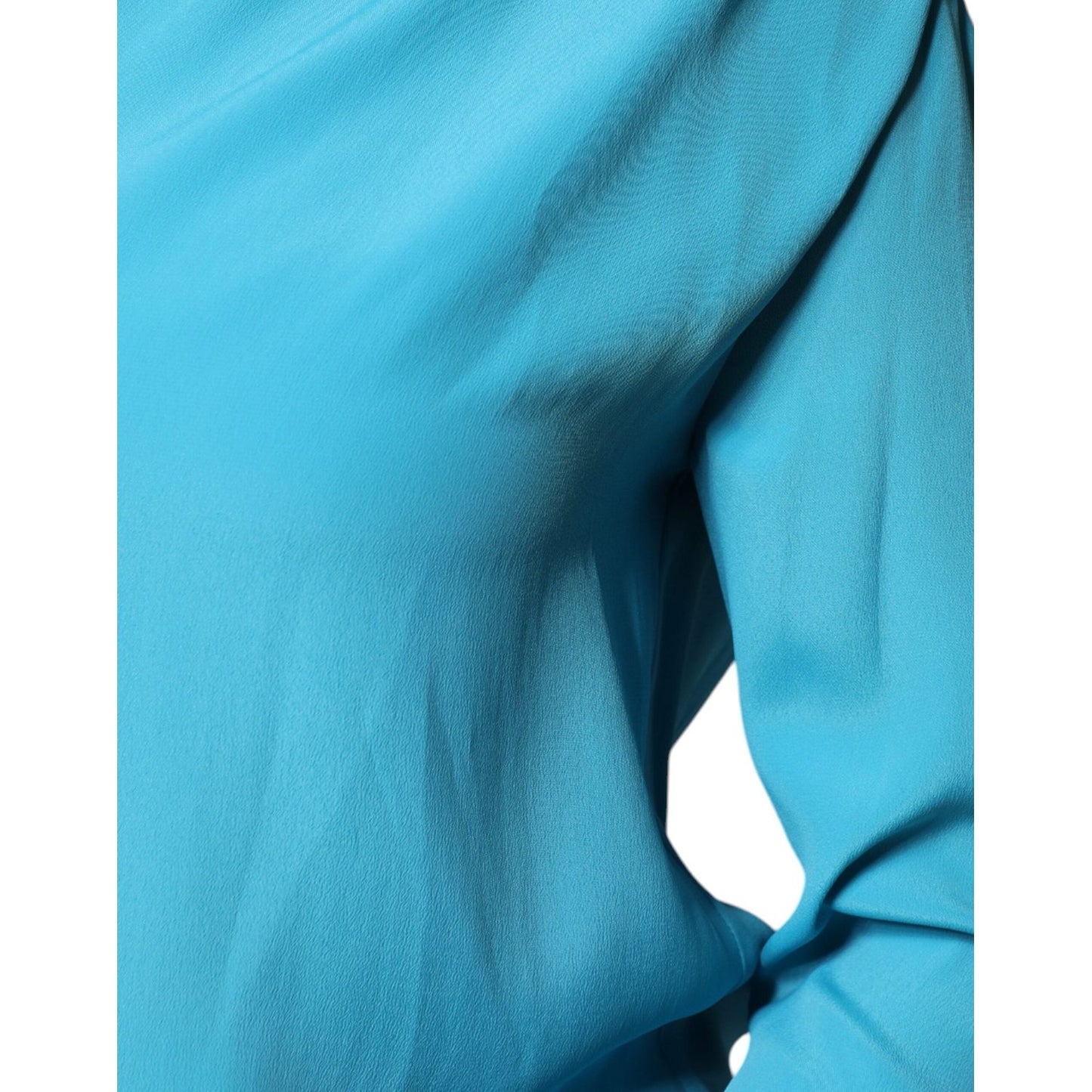 Close-up of Boutique Moschino blue blouse with round neckline and long sleeves, featuring minor pulled threads detail.