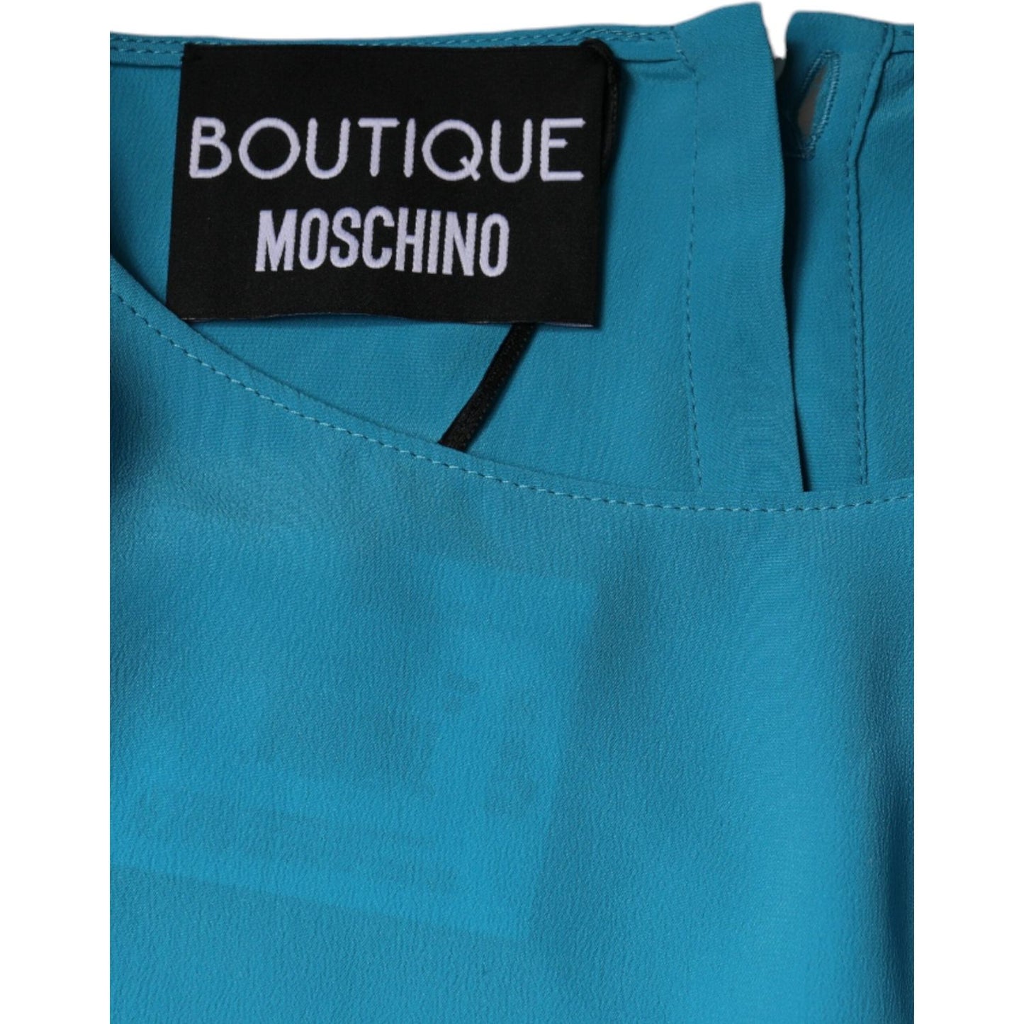 Boutique Moschino blue round neckline blouse with logo label and button closure.