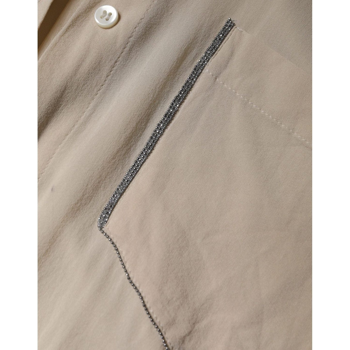 Close-up of Brunello Cucinelli beige silk blend top with button and pocket details.