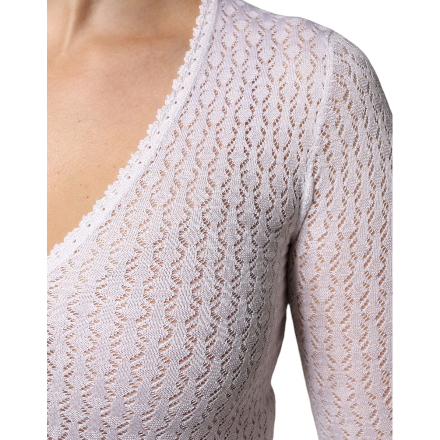 Close-up of white silk Dolce & Gabbana cardigan sweater with lace pattern and v-neck, showcasing intricate knit design and craftsmanship.