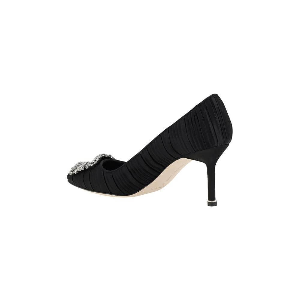 Side view of black Manolo Blahnik Hangisi Pumps with Swarovski crystal buckle and leather stiletto heel on white background.
