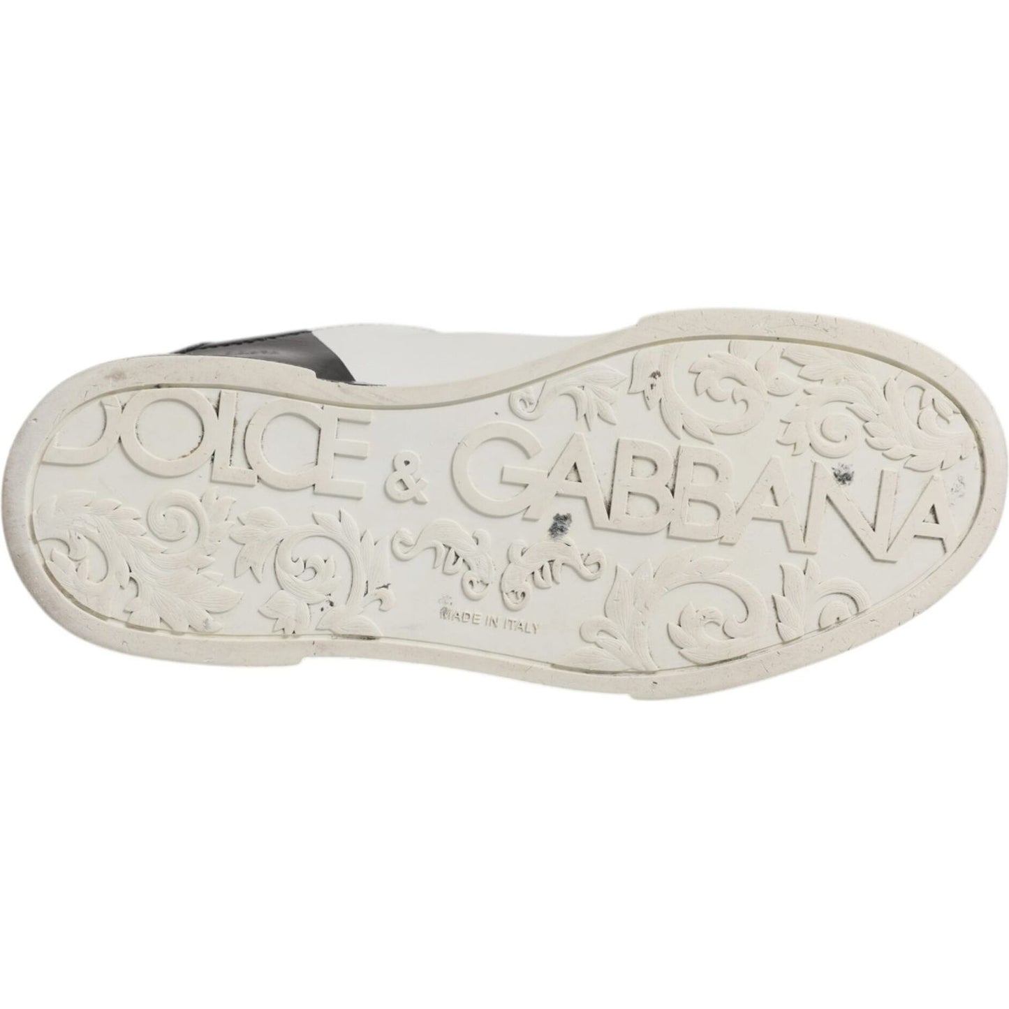 Underside of Dolce & Gabbana Portofino sneaker, showing engraved logo on rubber sole, white and black Italian casual shoe.