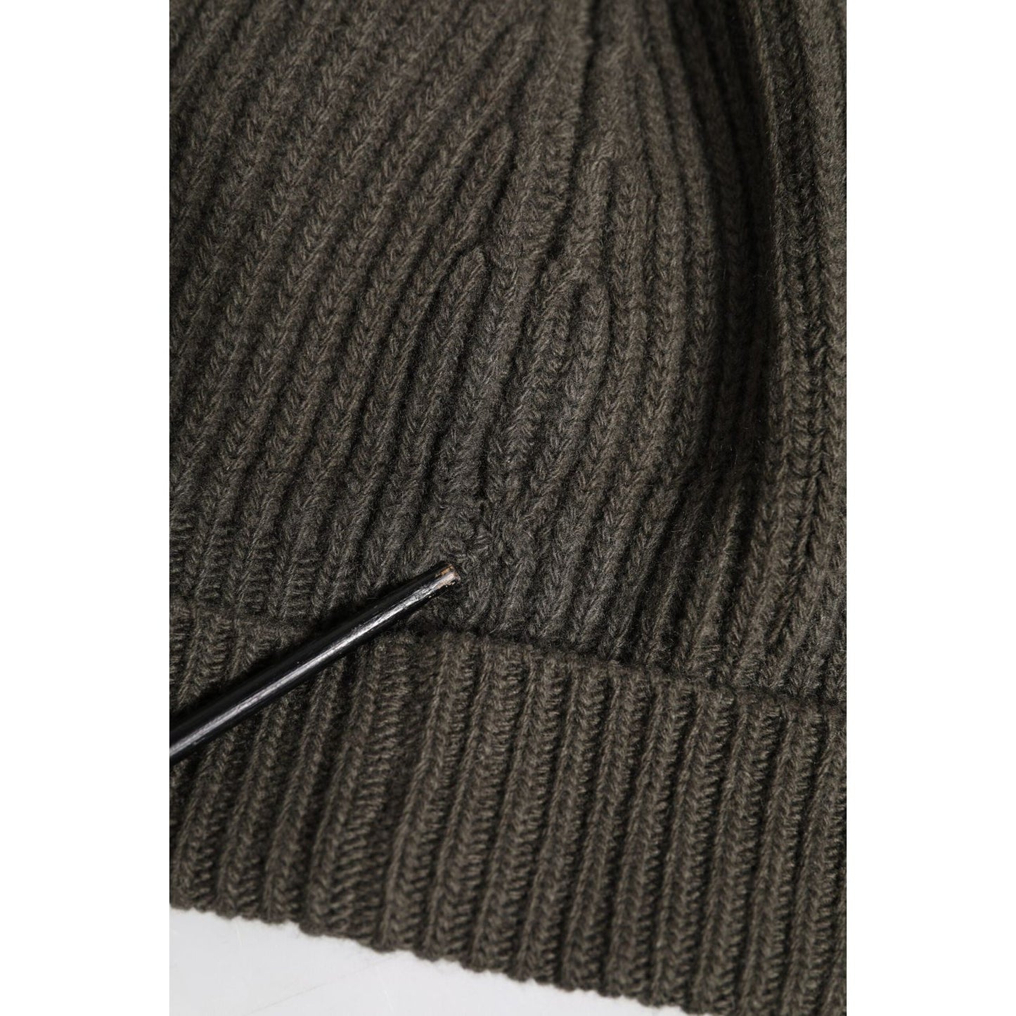 Close-up of a dark green Dolce & Gabbana wool and cashmere beanie with repaired rips, showing detailed ribbed knitting texture.