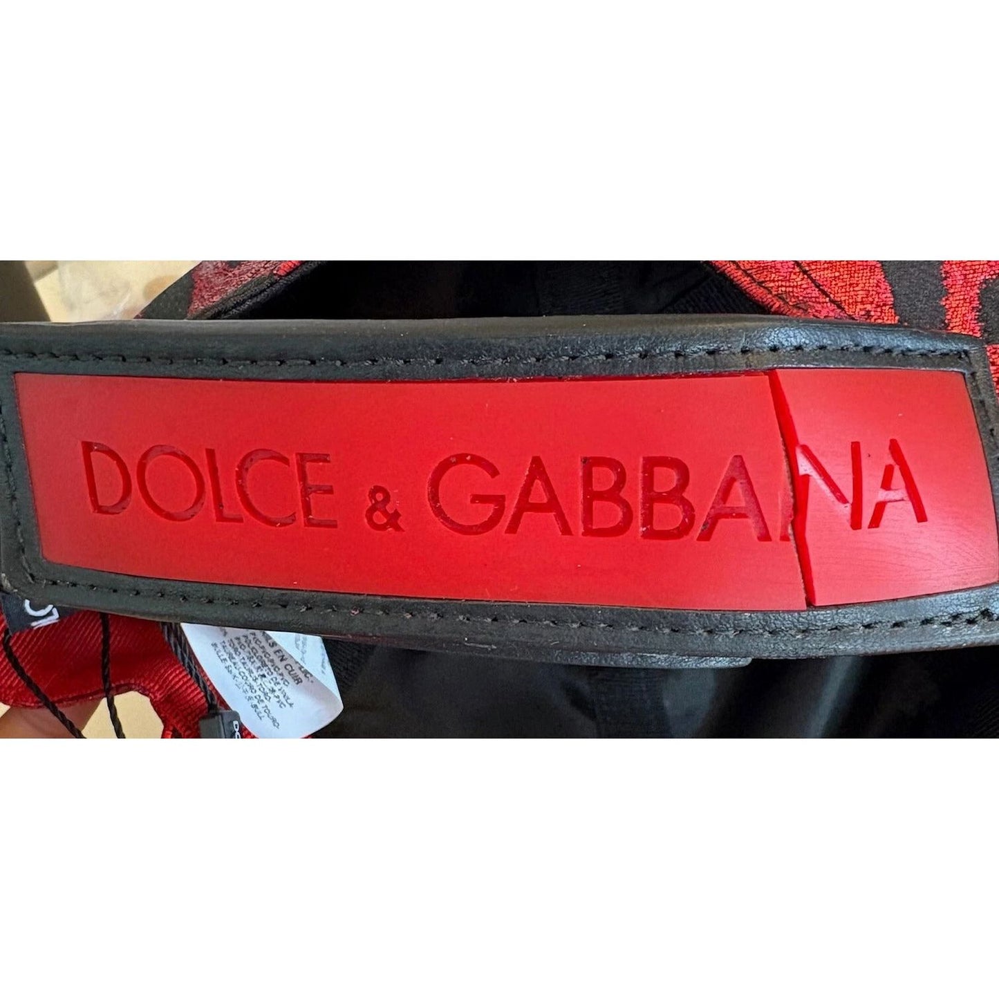 Close-up of Dolce & Gabbana baseball cap closure with crack, showing red leopard design and DG logo detail, made in Italy.