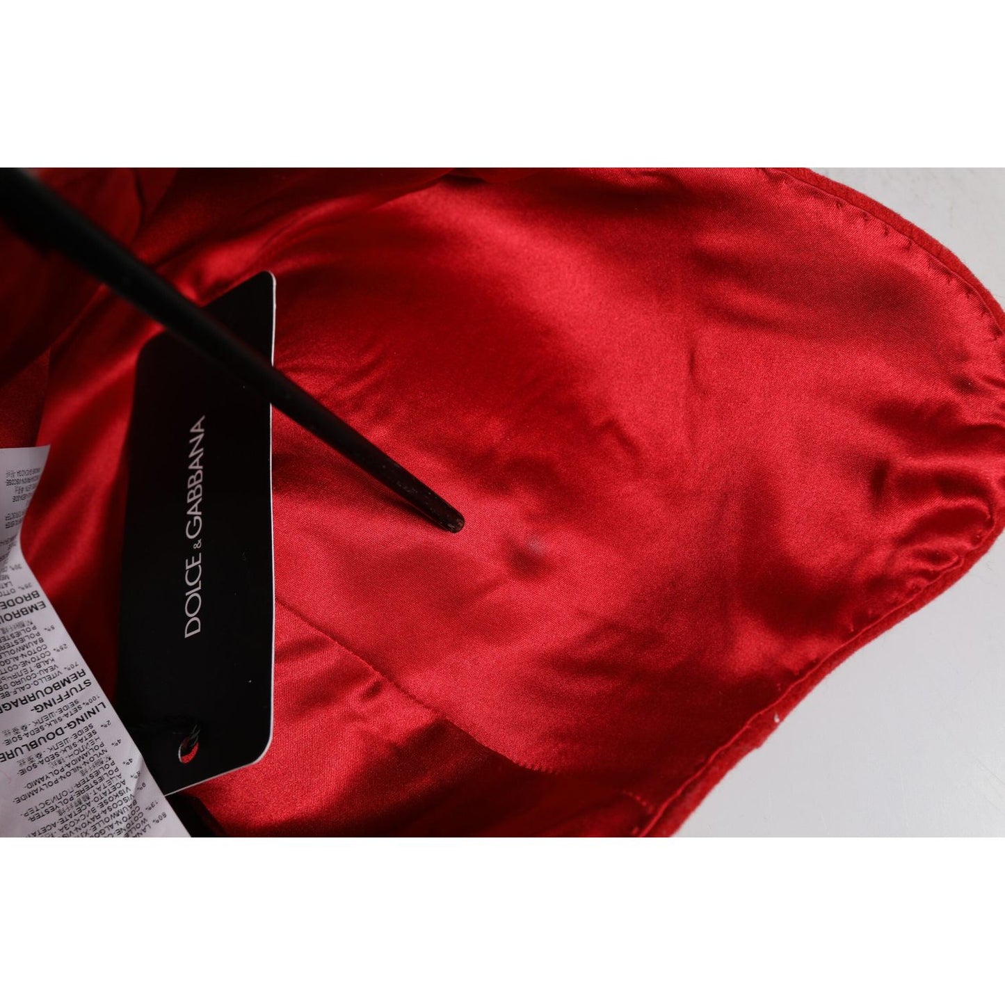 Inside view of Dolce & Gabbana red cloche hat showing silk lining, label, and visible stain on fabric.