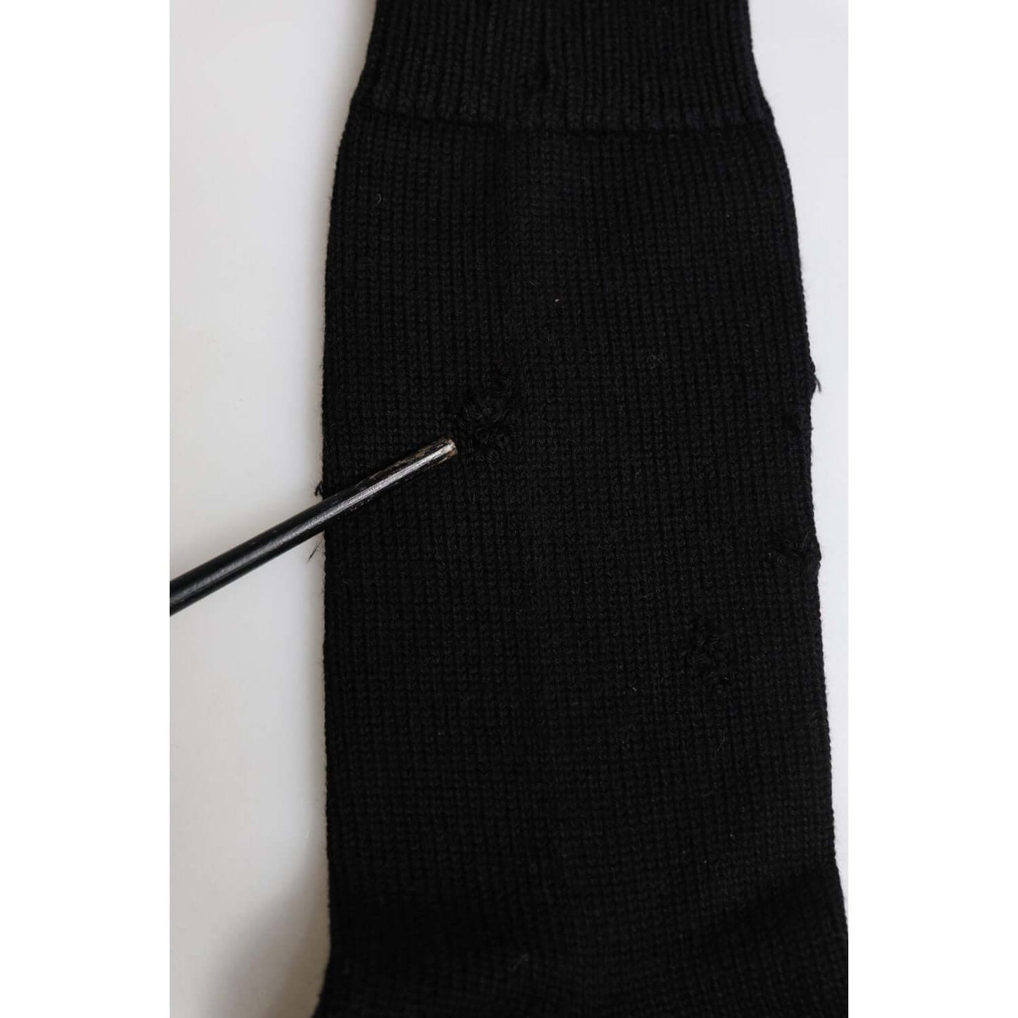 Close-up of Dolce & Gabbana black mid calf men's socks showing minor defect with holes and logo detail, made in Italy.