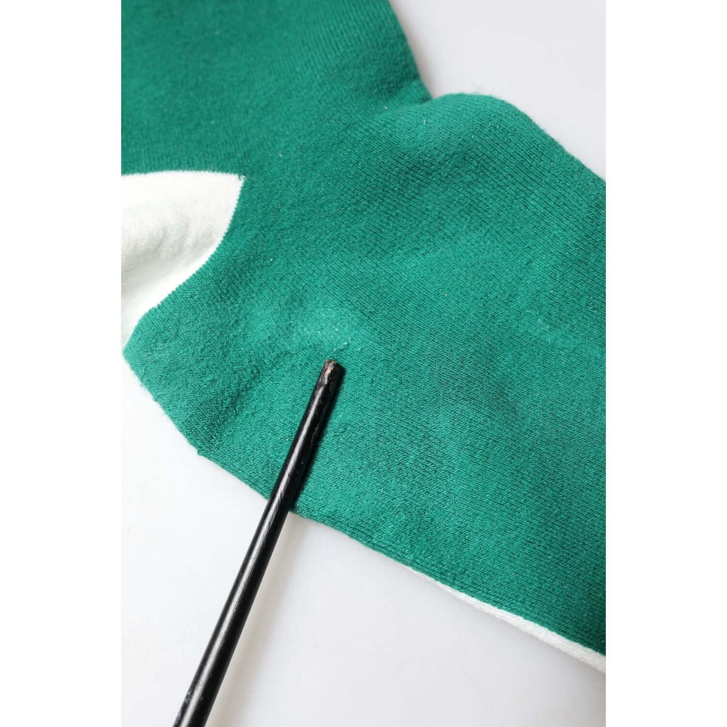 Close-up of Dolce & Gabbana multicolor sock showing stain detail on green fabric, part of store sample, cotton blend material.