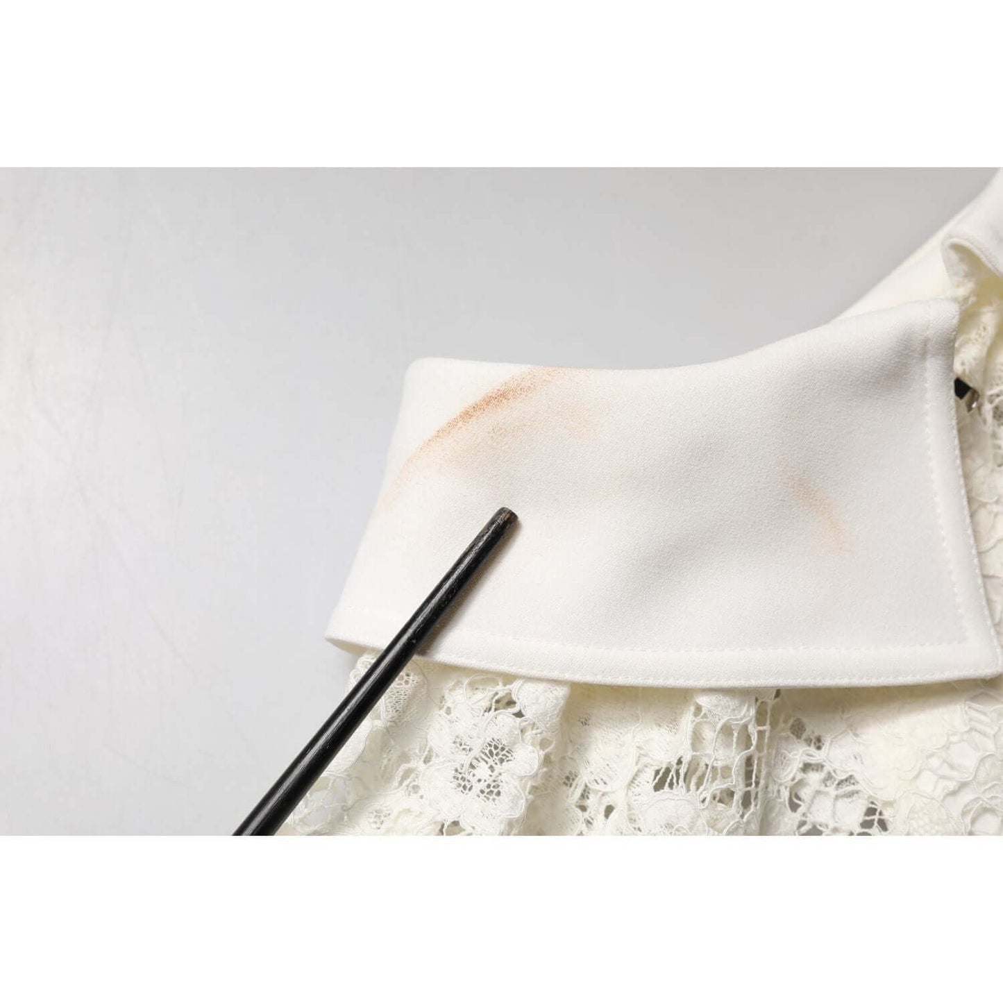 Close-up of makeup stains on Dolce & Gabbana white floral lace dress showing fabric texture and detailing.