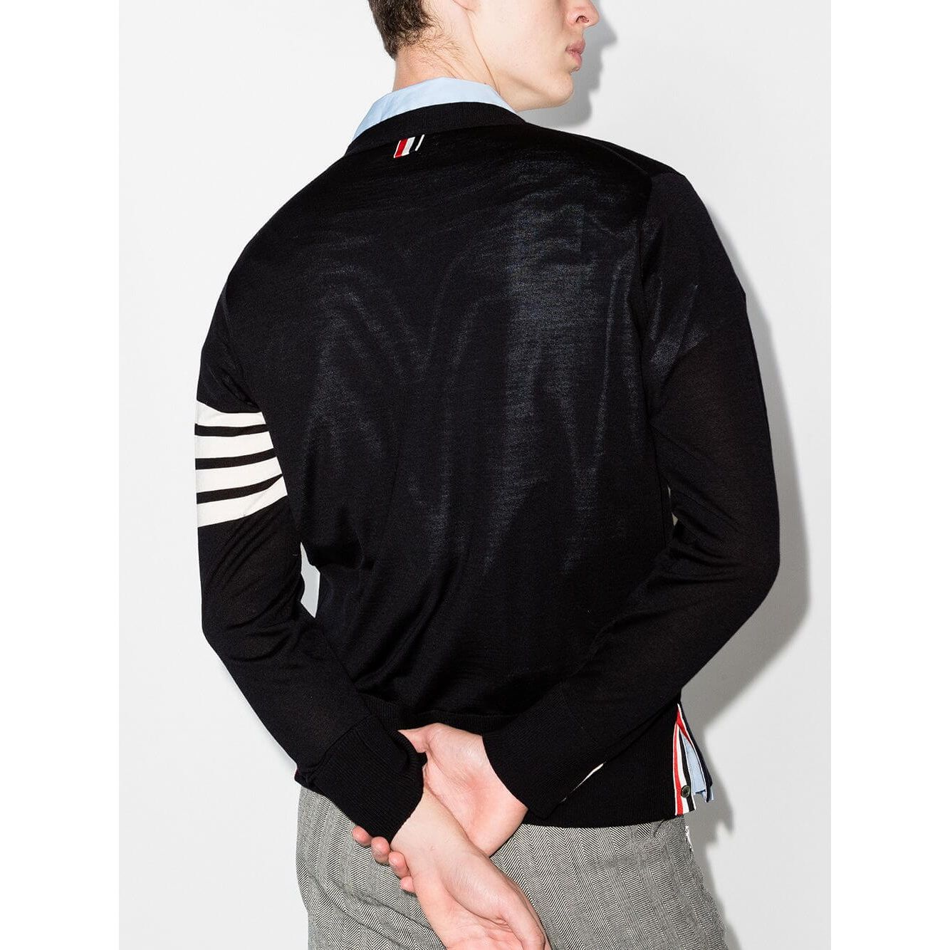 Model wearing Thom Browne Sweaters Blue with signature 4-Bar stripe, navy blue color, and side slits.
