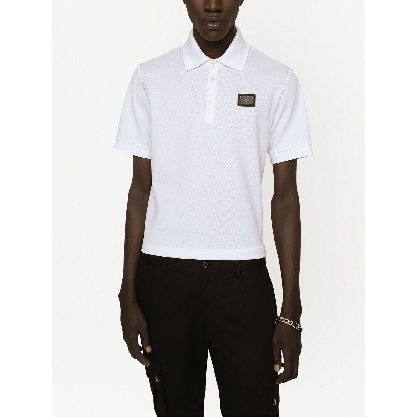 Model wearing Dolce & Gabbana Logo cotton polo shirt in white, featuring piqué weave, logo plaque, polo collar, and short sleeves.