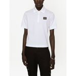 Model wearing Dolce & Gabbana Logo cotton polo shirt in white, featuring piqué weave, logo plaque, polo collar, and short sleeves.