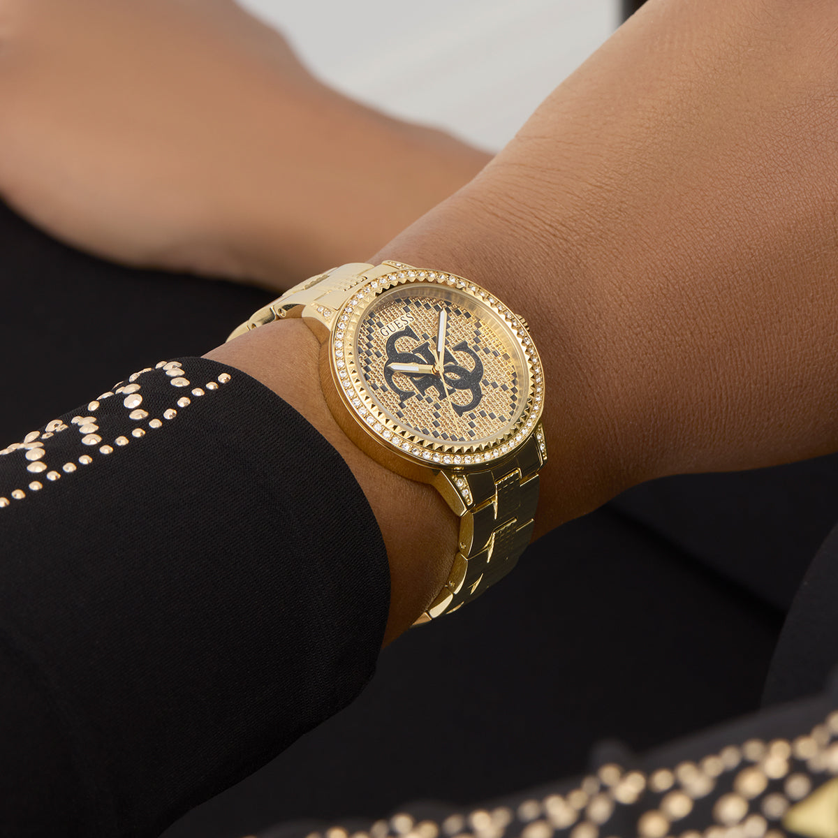 Person wearing gold watch, GUESS Mod. G LACE on wrist, close-up view.