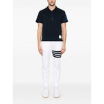 Model wearing Thom Browne Trousers White with elasticated drawstring waistband, side slit pockets, logo patch, and 4Bar cotton sweatpants.
